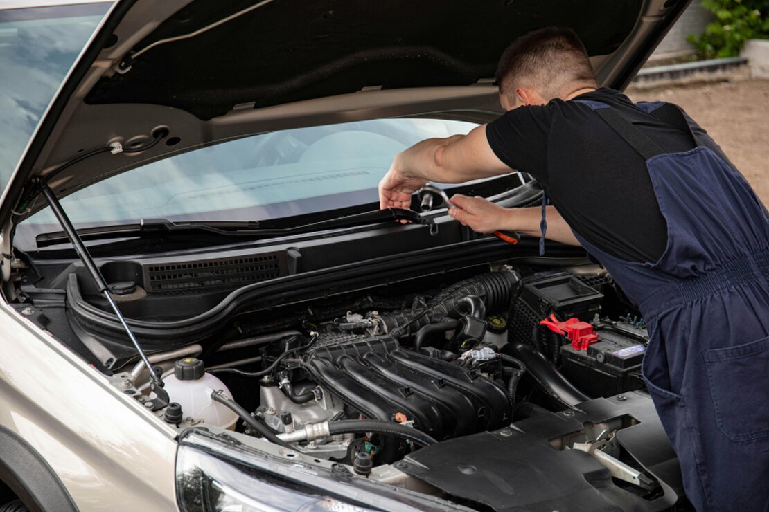 Mechanik serwisujący auto na poboczu autostrady